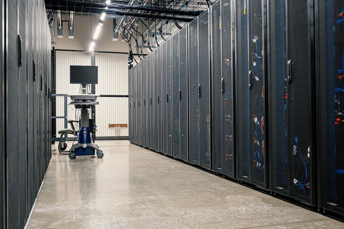 Inside a blue-lit data centre — rows of GPU servers